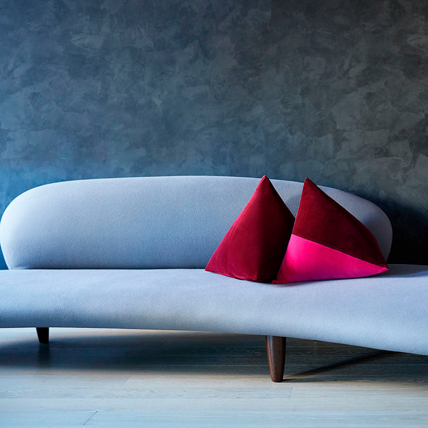 A burgundy and fuchsia Beija pillow on a tailored sofa